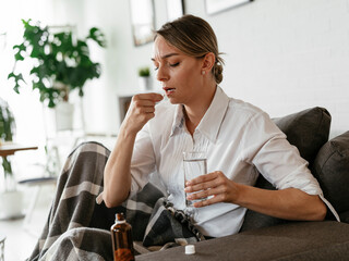 Young woman sick in bed. Woman drinking medicine, having stomach pain