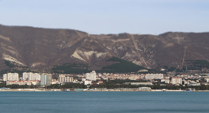 Spring view of the resort city of Gelendzhik, many buildings at the foot of the majestic mountains, warm and slightly cloudy weather and the beauty of nature. Russia, Black Sea coast