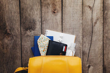 Flat lay travel concept, passport, wallet, bag, mask, notepad, wooden background