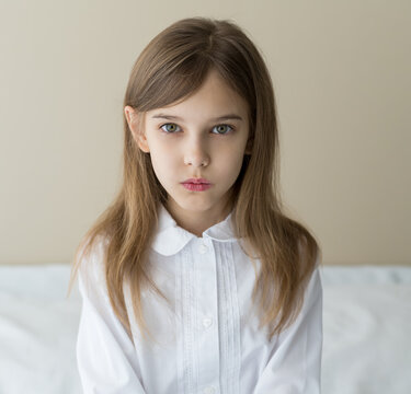 Close up shot of beautiful blonde caucasian little girl in a white shirt  with serious face expression