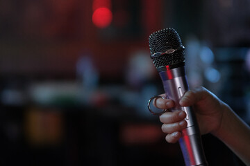 close up hand holding microphone in dark KTV room. Karaoke concept