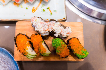 Close-up of Japanese sushi and sashimi food. Maki ands rolls with tuna, salmon, and fish egg. Top view of assorted sushi. Side view of assorted sashimi with tuna, salmon, shrimp, fish egg. 