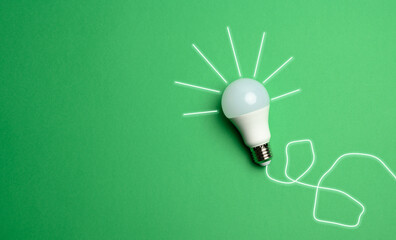 white light bulb with rays on a green background, green energy concept, new ideas
