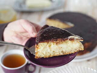 Cake making process. Women is hands serve a piece of freshly made homemade Enchantress cake covered with chocolate icing.