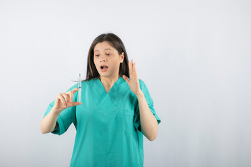 Portrait of female doctor holding a large syringe.