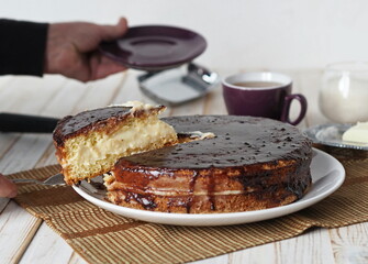 Cake making process. Women is hands cut a freshly made homemade Enchantress cake covered with chocolate icing into pieces for serving.