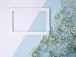 Frame border made with white field flowers on two tone pastel background. Creative spring layout with copy space for text. Floral composition. Flat lay, top view.