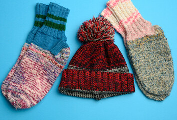 pair of warm comfortable knitted socks and a knitted hat on a blue background