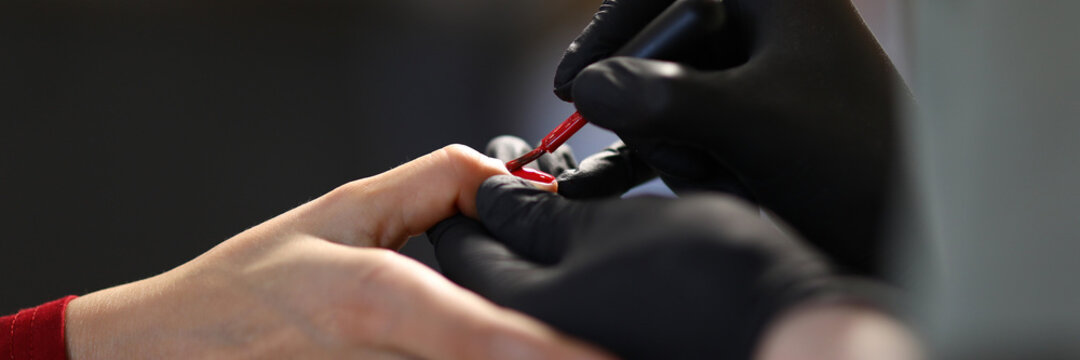 Manicurist paints the nails red. Manicure master training concept