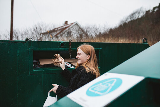Woman putting rubbish into recycling bin