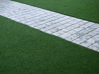 stone pathway on green artificial grass of lawn texture