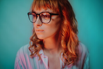 Beautiful girl on a blue background wearing glasses. A student wears glasses in the evening in neon