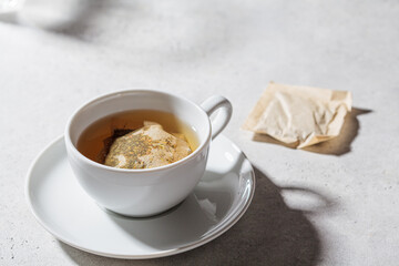 Fresh herbal tea in white cup. Herbal tea bags, copy space.