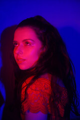 Photo of a woman in neon, beautiful photo in a teen club. Red-blue color. Woman portrait, eye makeup and earrings. Music and dance. Fashion portrait of young elegant