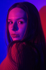 Photo of a woman in neon, beautiful photo in a teen club. Red-blue color. Woman portrait, eye makeup and earrings. Music and dance. Fashion portrait of young elegant