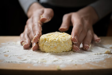 Women's hands form, sculpt cottage cheese pancakes on a wooden plank close-up