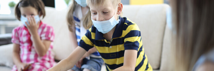 Children in medical protective masks play board games at home. Educational games during coronavirus quarantine concept