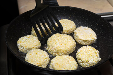 Many cottage cheese pancakes fried for breakfast in a black pan close-up