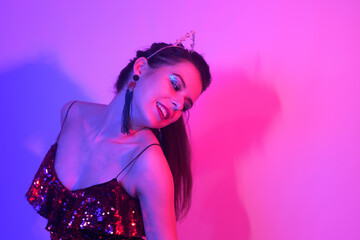 Gorgeous girl dancing in a neon light. A girl in a red shiny dress and with cat ears is dancing at a party. Smile dance in neon