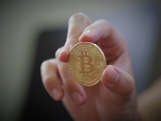 A man hold a golden coin of bitcoin(BTC). A cryptocurrency made by Satoshi Nakamoto