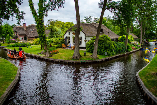 Giethoorn, Netherlands - July 6, 2019: People paddling boats on the canals of Giethoorn village, known as the Venice of the Netherlands