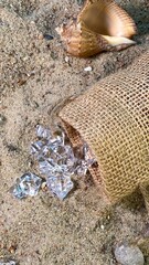 Crystals falling out of the jute bag on the sand visible stones and shells