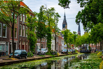 Delft, Netherlands - July 11, 2019: Scenic view of canals of Delft with towers of the Nieuwe Kerk ('New Church') in the background