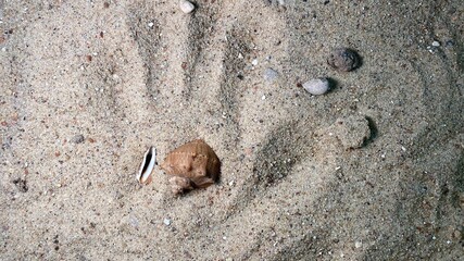 reflection of a hand in the sand with visible stones G © Józef