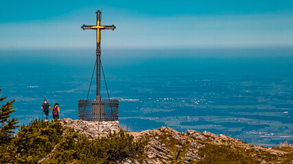 Beautiful alpine autumn or indian summer view with a summit cross at the famous Hochfelln summit, Bergen, Bavaria, Germany