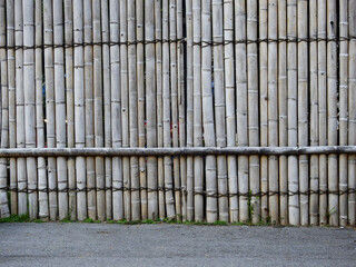 aged bamboo wall with asphalt road