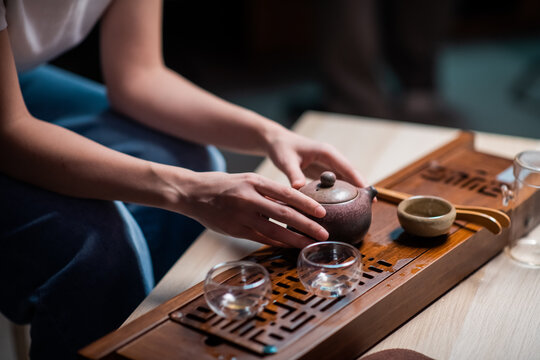Traditional chinese yixing clay teapot in women's hands close-up. A girl performs the sacrament of an oriental tea ceremony at home for her husband