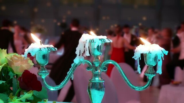 Dancing couples, burning candle and beautiful flowers. Traditional Vienna ball.