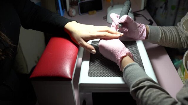 Manicurist removing cuticle from the girl client nail at beauty salon. Master manicure