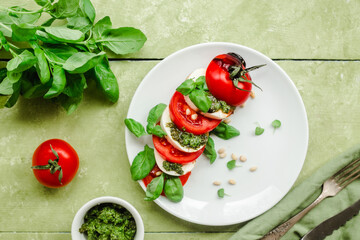 Caprese salad in a white plate on a green table