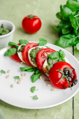 Caprese salad in a white plate on a green table