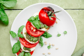 Caprese salad in a white plate on a green table