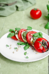 Caprese salad in a white plate on a green table