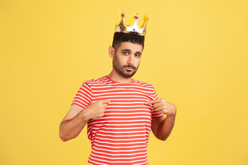 I'm king! Ambitious bearded man wearing golden crown and pointing himself, looking with arrogance,...