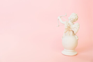 figurine of an angel Cupid with a bow on a pink background. Valentine's Day.