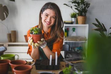 Woman taking care of plants at her home. Smiling young woman holding a succulent plant.
