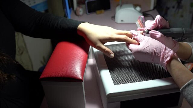 Manicurist removing cuticle from the girl client nail at beauty salon. Master manicure