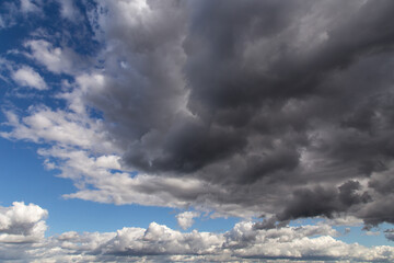 Storm sky. Dark grey and white big cumulus clouds against blue sky background, cloud texture, thunderstorm