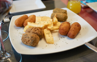 plate of assorted traditional Spanish homemade croquettes on a white plate with fork. Tapas food.