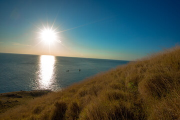Naklejka premium The natural background of the morning light rising in the middle of the sea and surrounded by mountains, cool breezes, the beauty of the ecology of the tourist attractions.