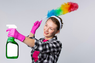 Beautiful blonde woman wearing house clothes and gloves wiping the cobweb while smiling confidently and happily. Cleaning spray with empty space for ad