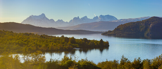 Panoramic view of a landscape with mountains and lake in late afternoon light