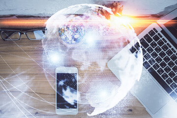 Double exposure of business theme hologram over desktop with phone. Top view. Mobile international trade connection concept.