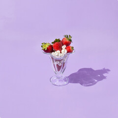 Creative concept with strawberries, white pearls  and glass jar on bright purple background. Abstract fruit or food layout. Optimistic spring idea.