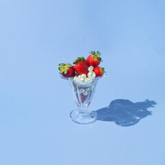 Creative concept with strawberries, white pearls  and glass jar on pastel blue background. Retro fruit or food layout. Romantic spring idea.