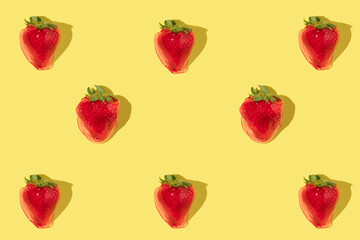Cretive idea with strawberries in jelly on bright yellow background. Minimal flat lay. Fun spring composition with fruits.